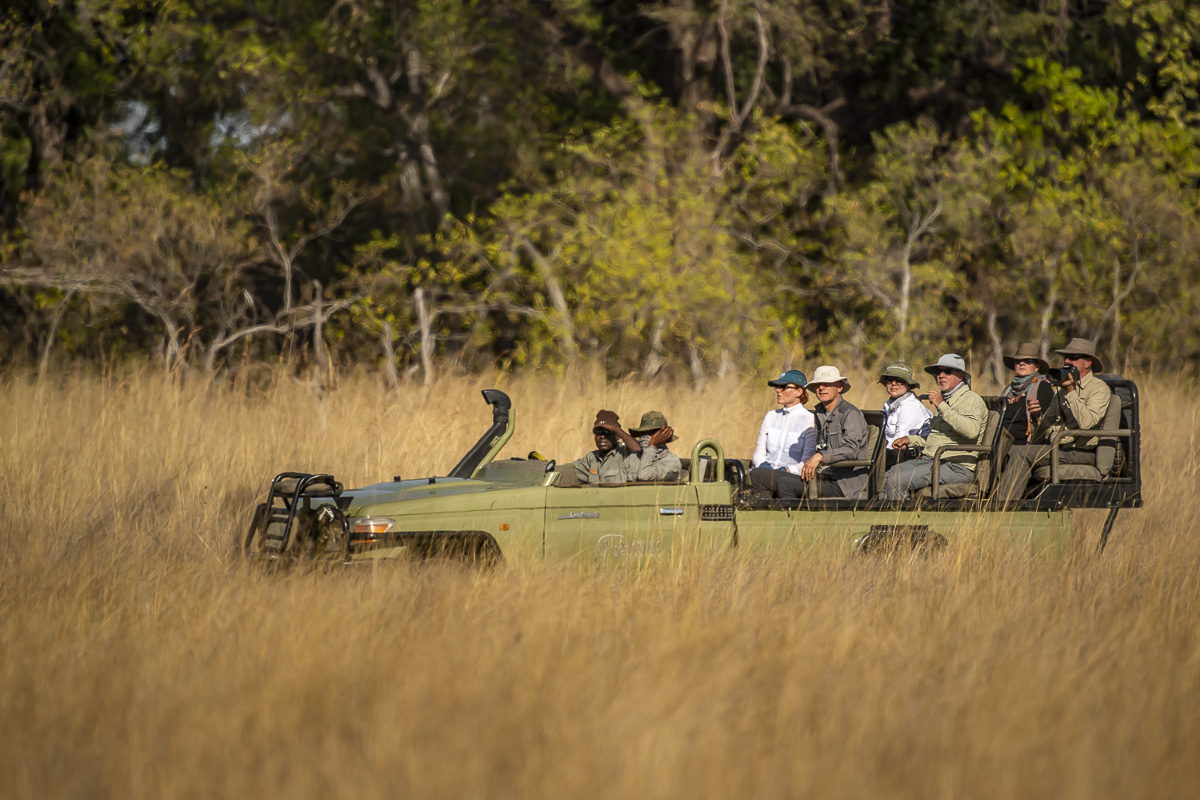 Safari vehicle with tourists driving across the grassland